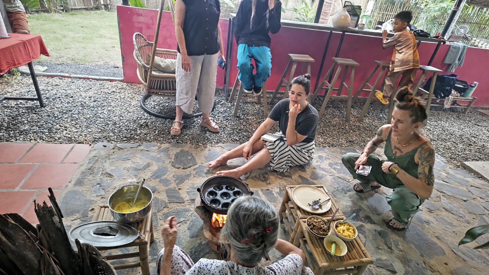 Guests joining a family cooking class around a wood-fired stove