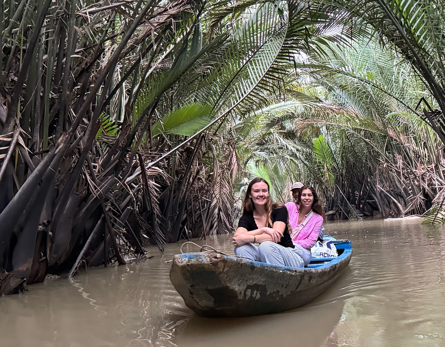 Travelers in a hand-rowed sampan on a small nipa-palm canal in Ben Tre