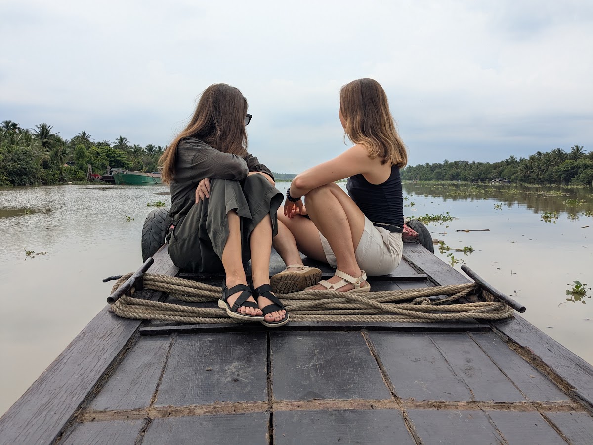 Two travelers sitting together at the bow of a wooden boat
