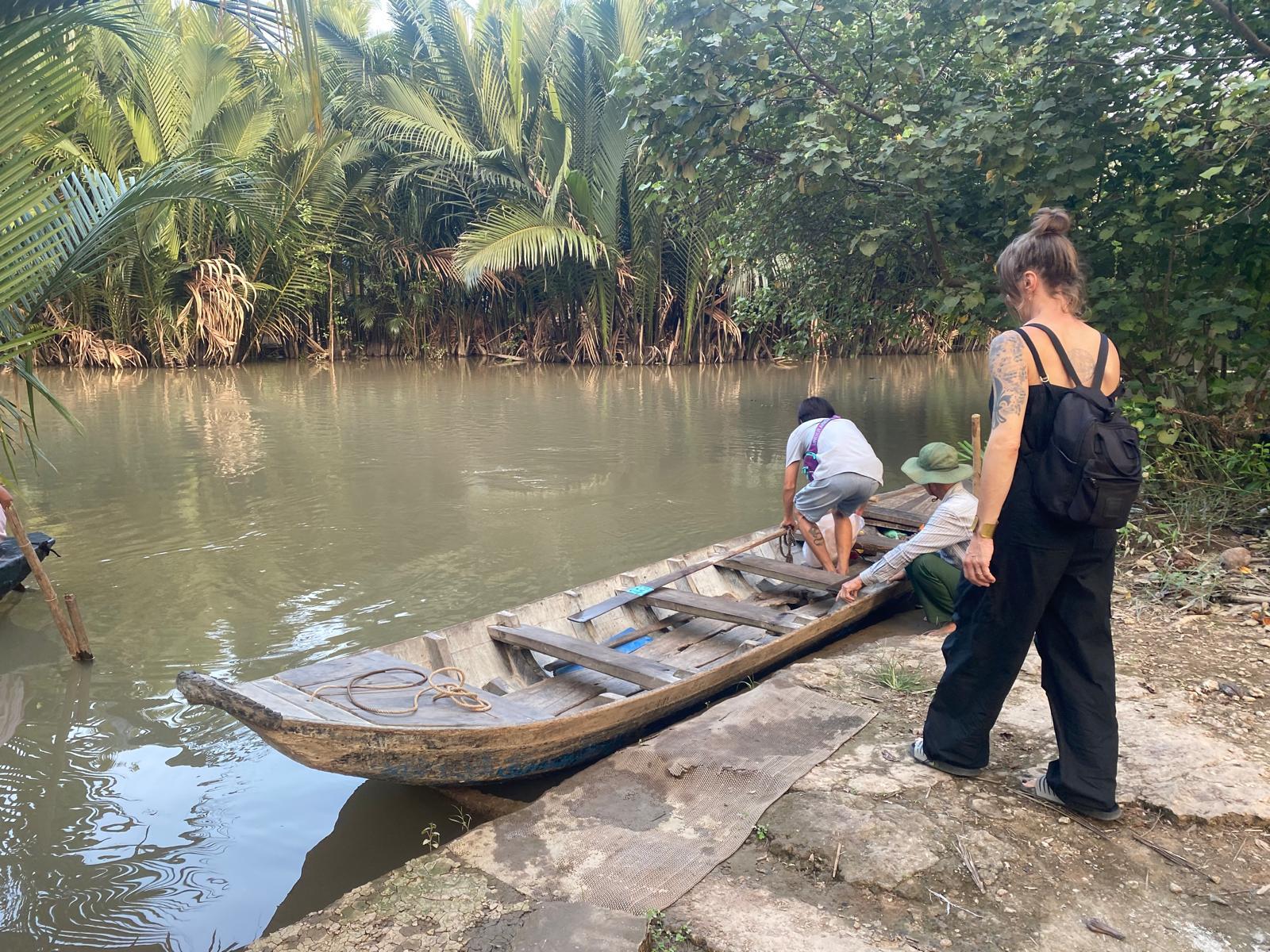Local rower preparing a wooden sampan at a small canal landing in Ben Tre