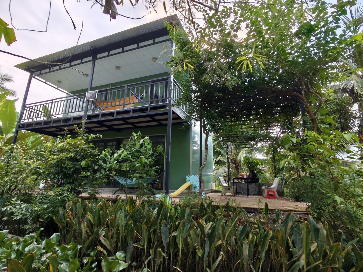 Private two-bedroom house with an upstairs balcony and shaded bougainvillea terrace at Coco Happy Farm